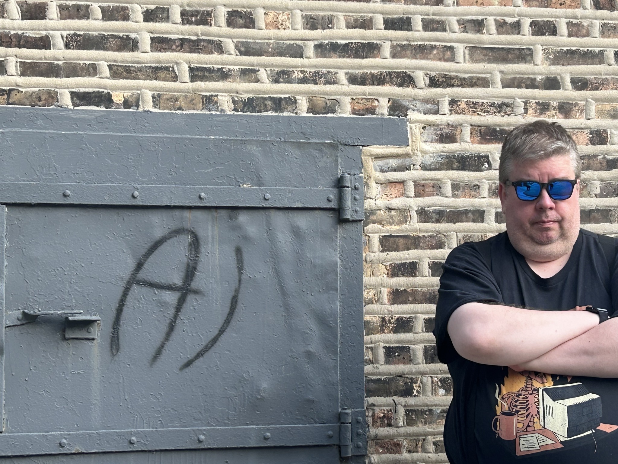 Al Iverson standing beside an iron door marked “Al” in a brick wall